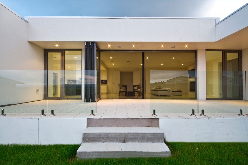 Aluminium bifold doors open onto a villa terrace at dusk