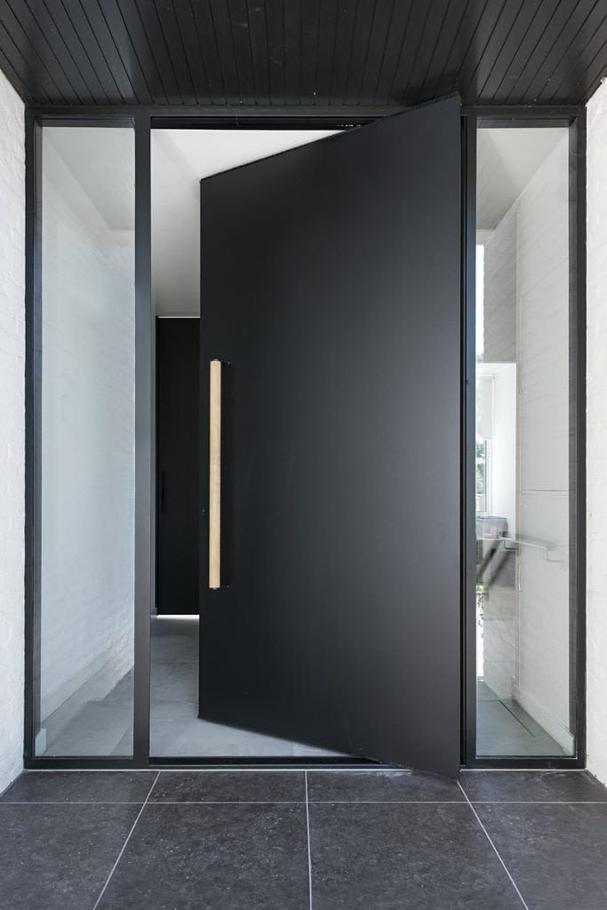 Luxury black aluminium pivot entrance door with vertical handle, modern villa