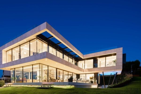 Two-storey villa with full-height aluminium lift-and-slide doors, a type that reaches air permeability Class 4 because the sash is lowered onto its seals
