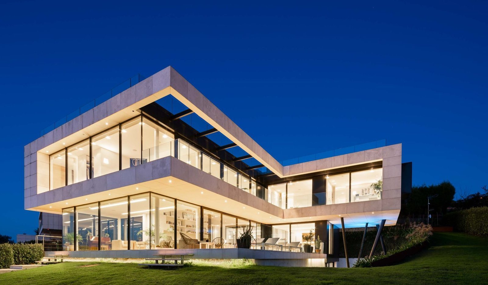 Two-storey villa with full-height aluminium lift-and-slide doors, a type that reaches air permeability Class 4 because the sash is lowered onto its seals